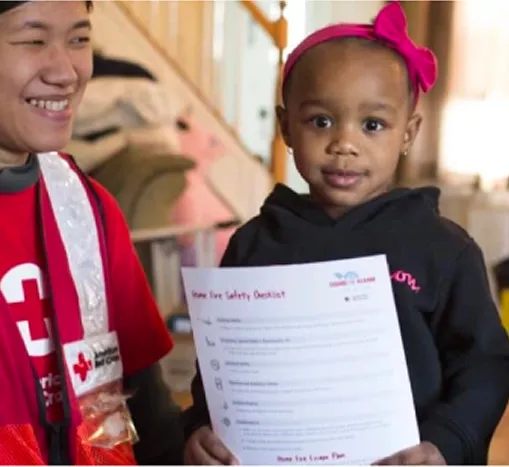 Healthcare worker smiling next to a child holding a paper